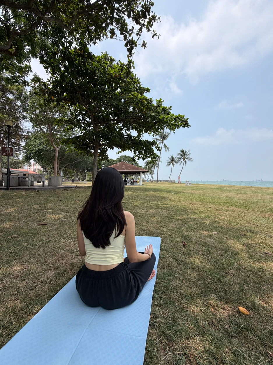 a yoga teacher sitting on a mat along the beach